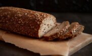 Skivet, frørikt grovbrød på et trebrett med bakepapir